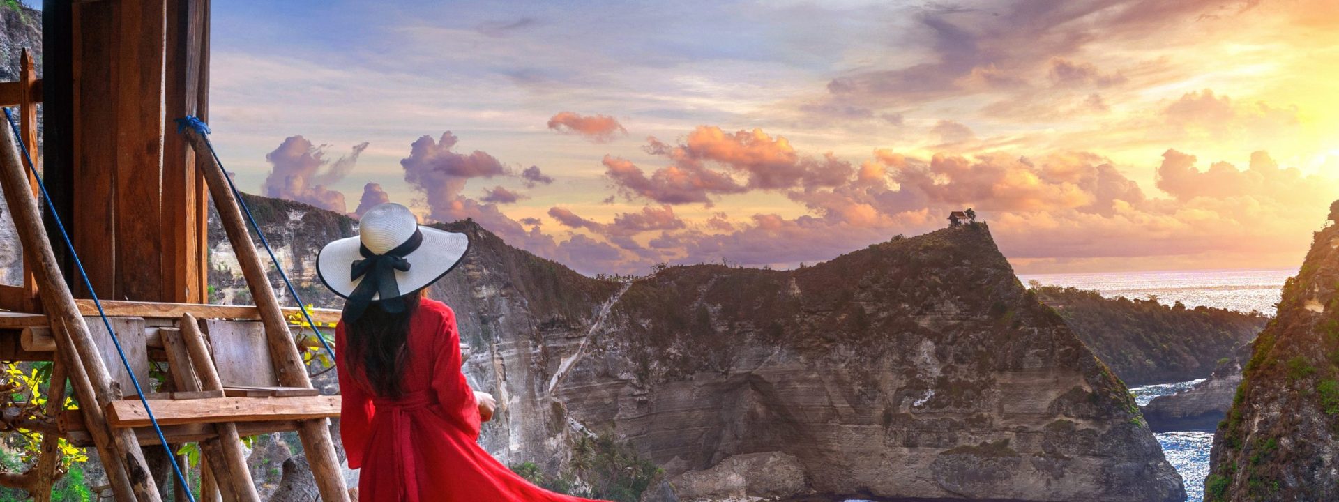 Young girl on steps of house on tree at sunrise in Nusa Penida island, Bali in Indonesia.
